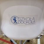 Logo Szkoły Dookoła na krześle obrotowym