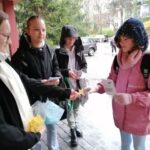 Wolontariusze rozdają kwiaty uczniom przychodzącym do szkoły